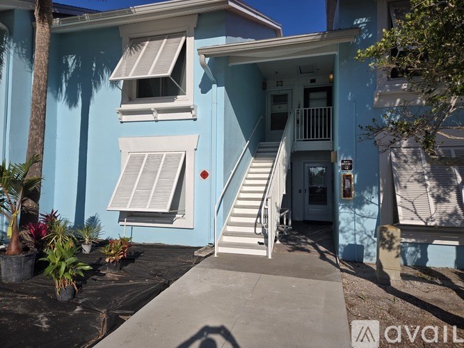 A blue house with a white door and stairs leading to the entrance.