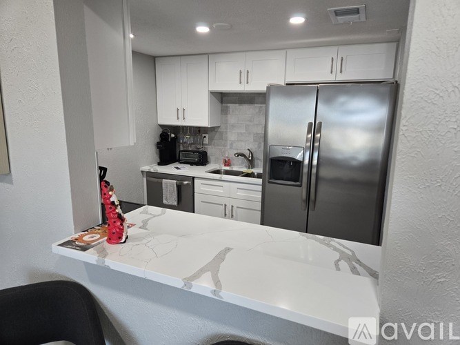 A kitchen with white cabinets and a marble countertop.