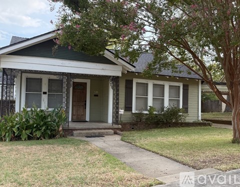 A small house with a front porch and a brick walkway leading to the front door.