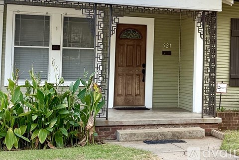 A house with a grey roof and a porch with a tree in front.