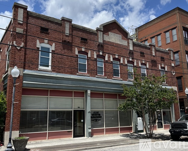 A street view of a red brick building with a sign that reads "AVAIL".