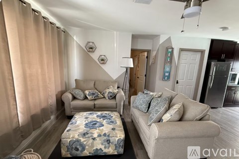 A living room with a beige couch and a floral ottoman.