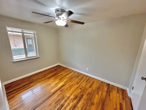 A room with a ceiling fan and wooden flooring.