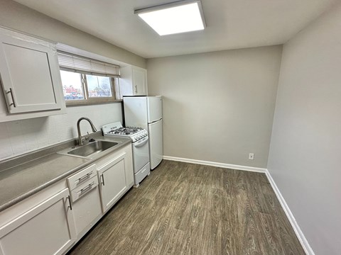 A kitchen with white cabinets and a wood floor.