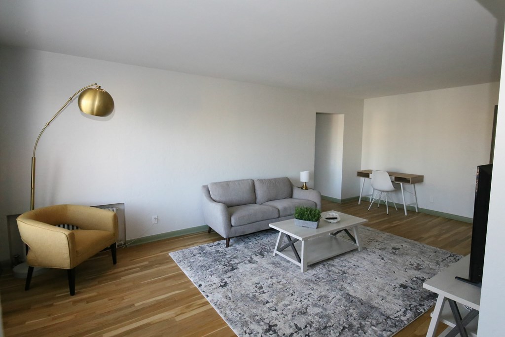 A living room with a grey sofa, a yellow chair, a coffee table, and a floor lamp.