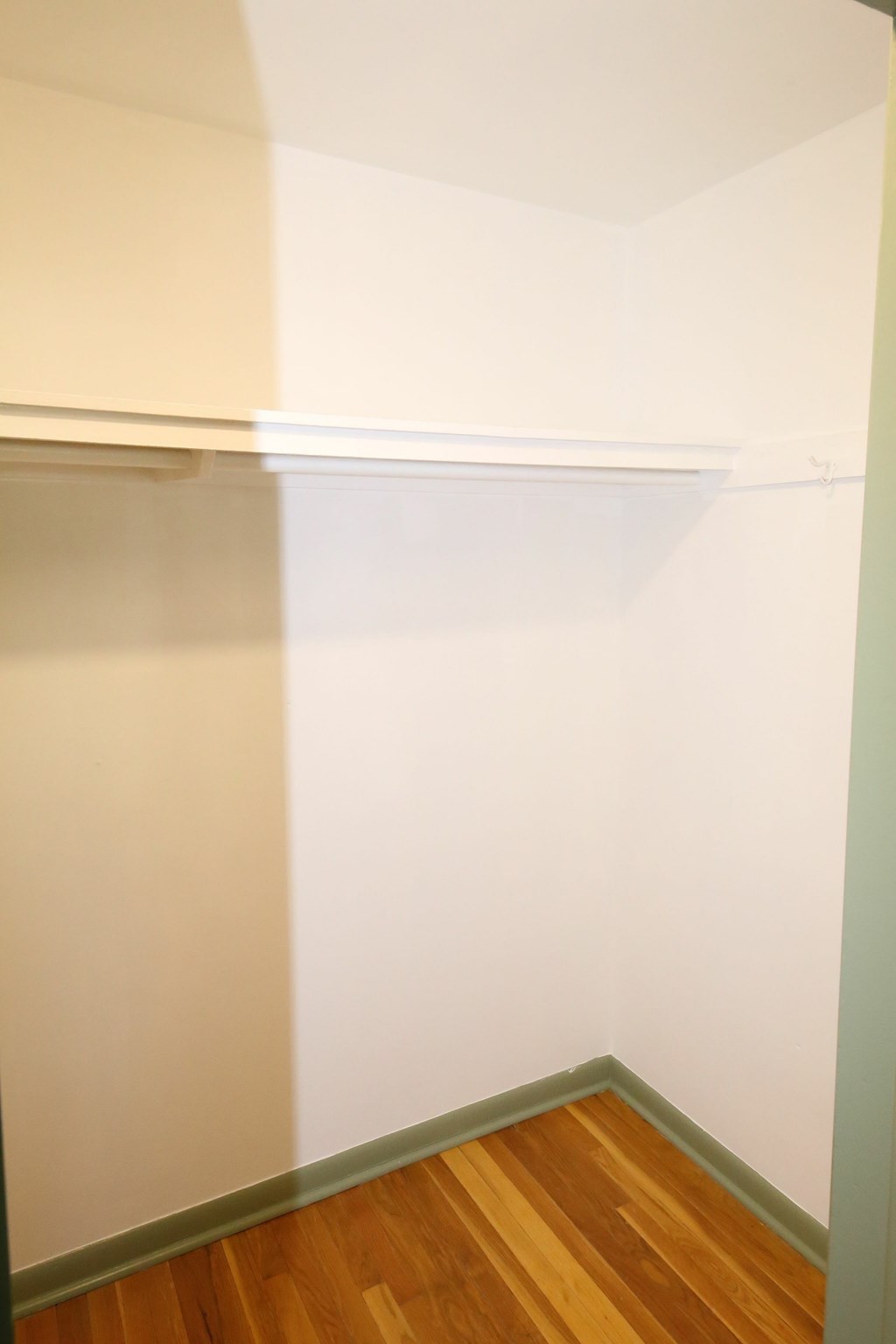 A white shelf in a room with wood flooring.