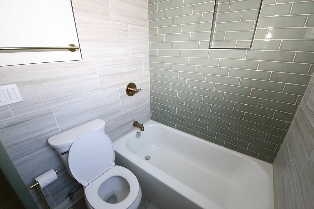 A white toilet sits next to a bathtub in a bathroom.