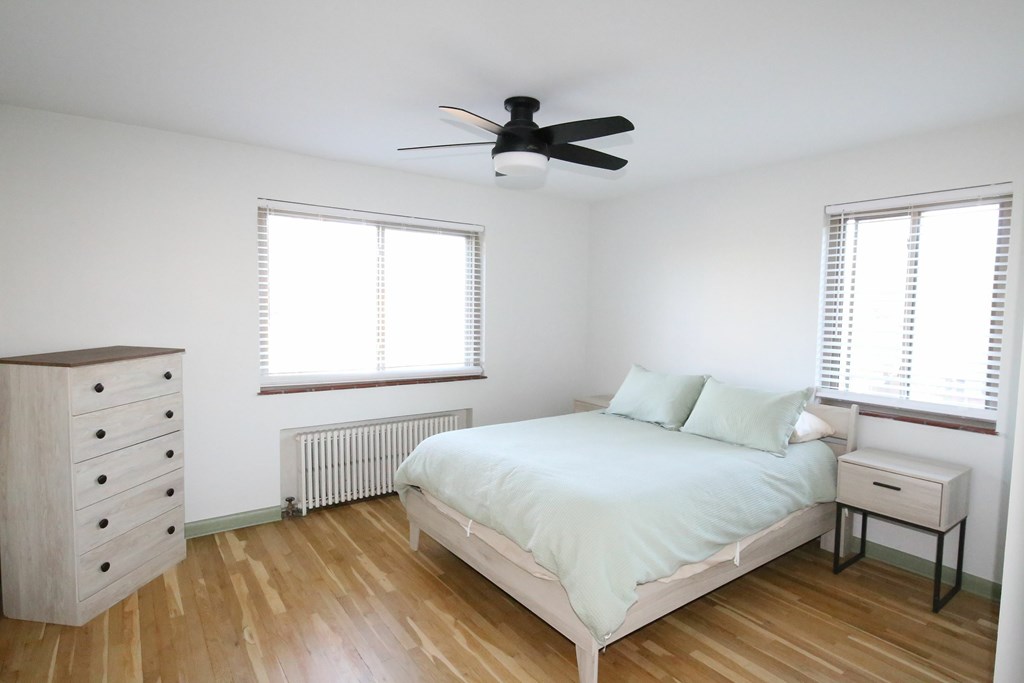 A bedroom with a bed, dresser, and window.