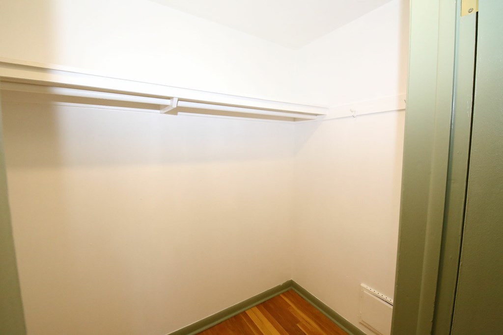 A white wall with a wooden floor and a white shelf.