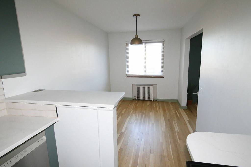A kitchen with white cabinets and a window with blinds.