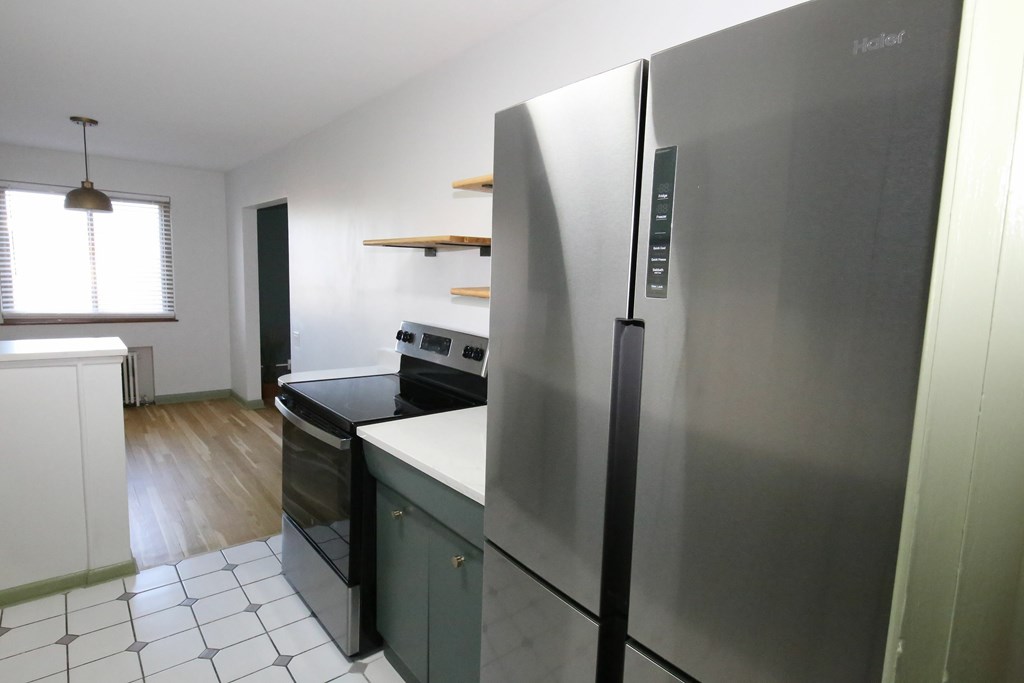 A kitchen with a stainless steel refrigerator and a black oven.