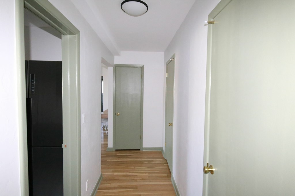 A long hallway with a black door on the left and a white door on the right.