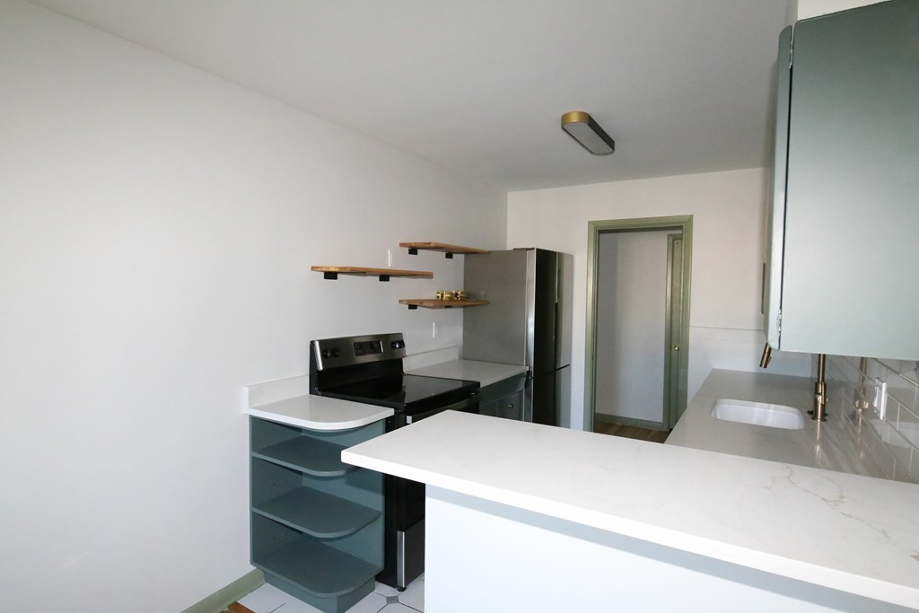 A white countertop with a sink and a black oven.