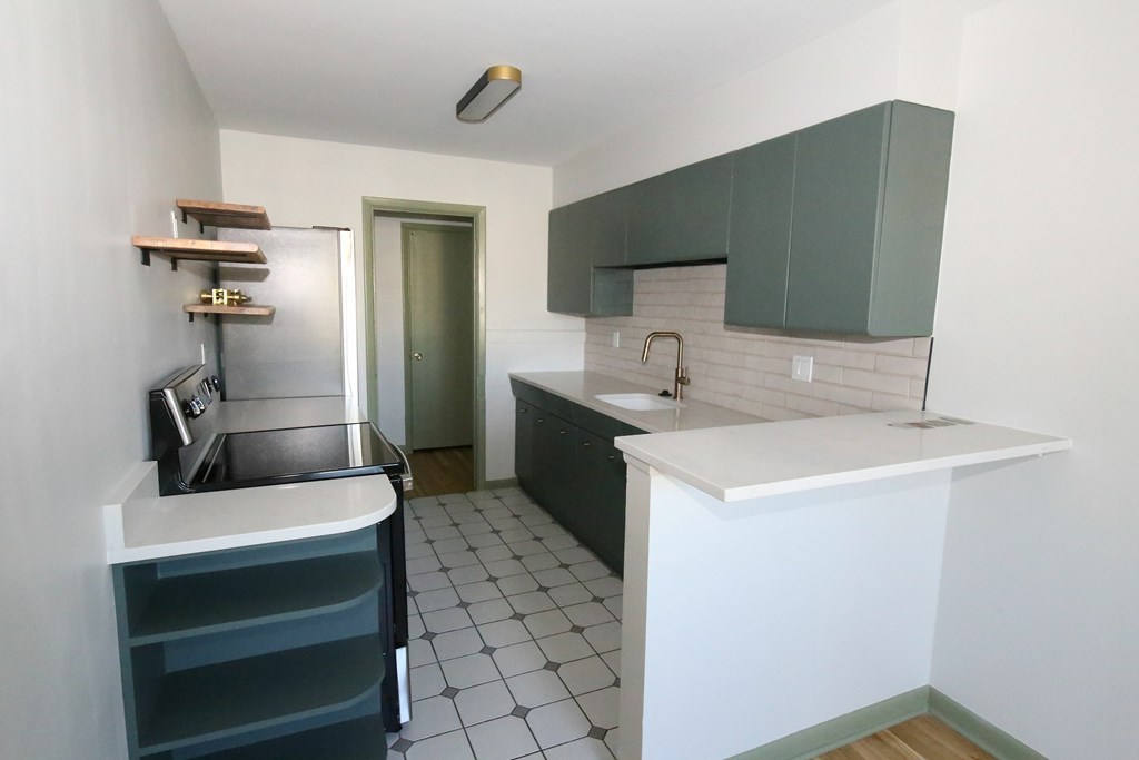 A kitchen with a white counter top and green cabinets.