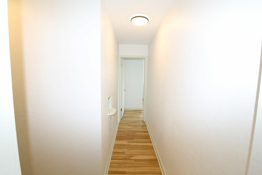 A long hallway with wood floors and white walls.