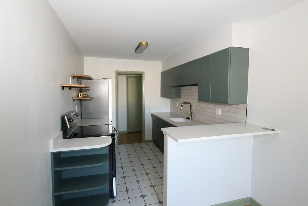 A kitchen with white countertops and green cabinets.
