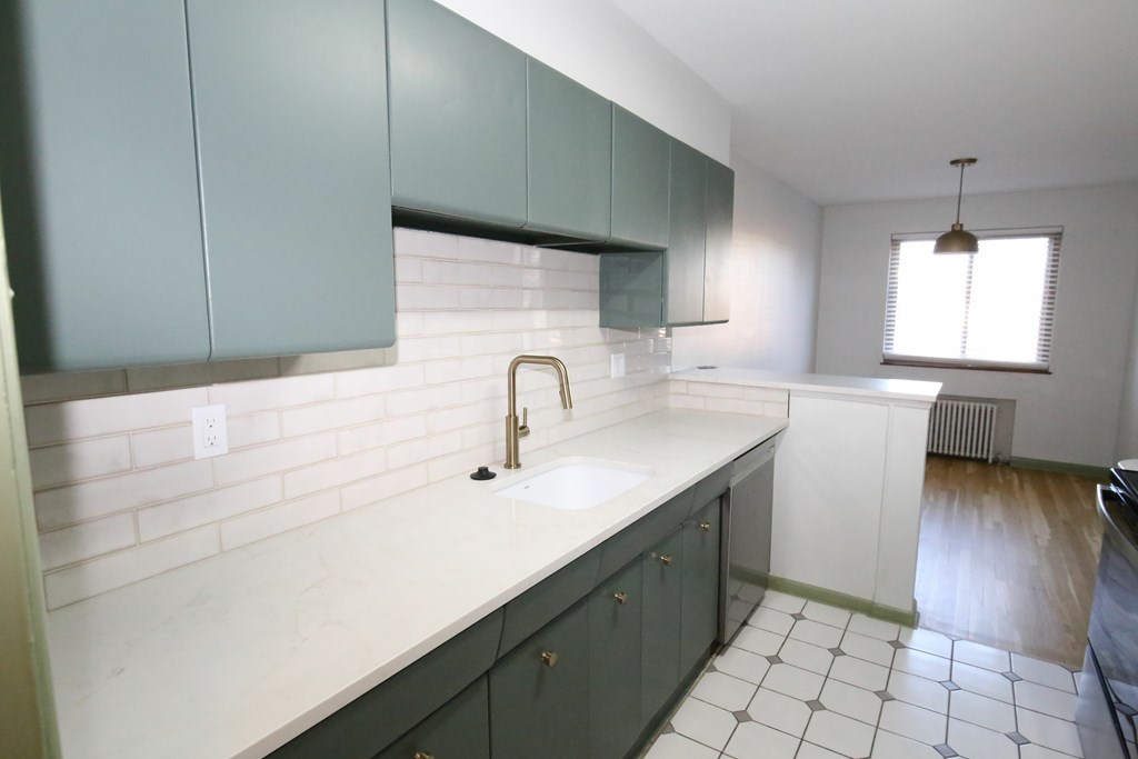 A kitchen with white tiles and green cabinets.