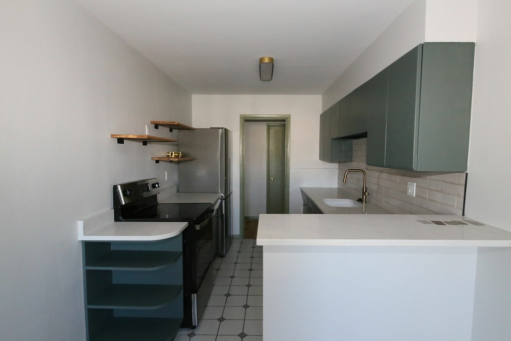A kitchen with white countertops and black appliances.