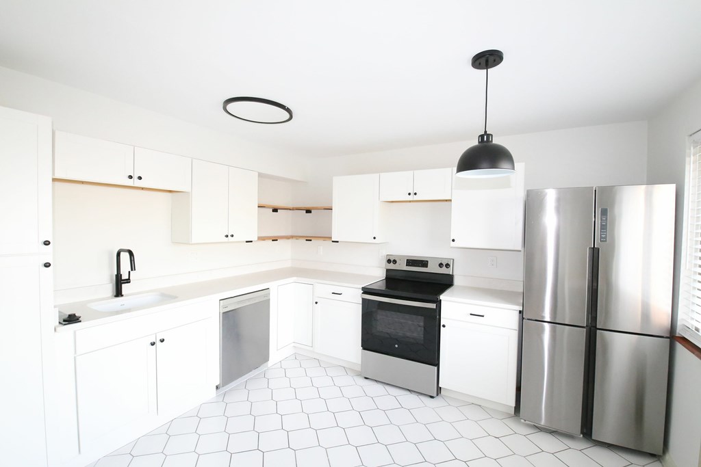 A modern kitchen with white cabinets and stainless steel appliances.