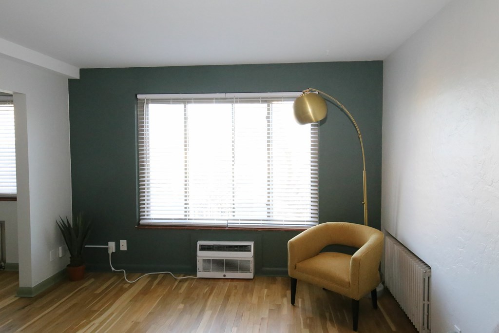 A room with a yellow chair and a window with blinds.