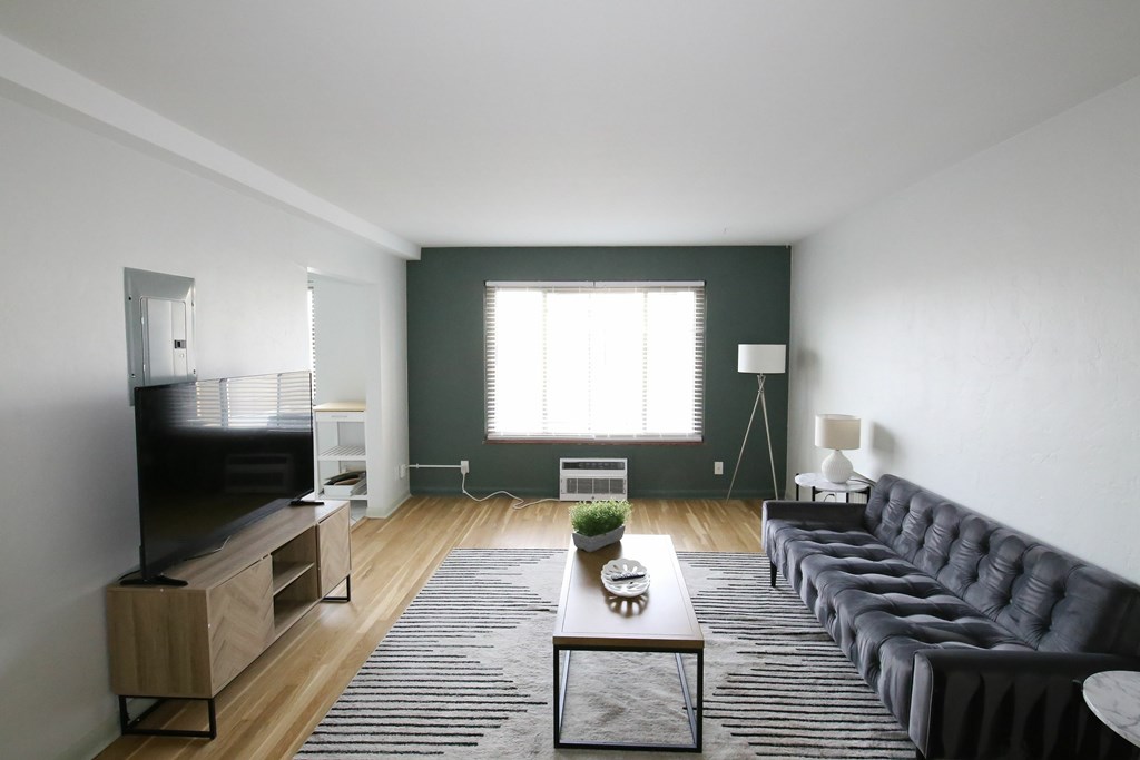 A living room with a grey sofa and a wooden floor.