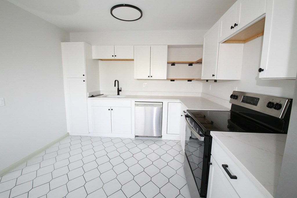 A kitchen with white cabinets and black appliances.