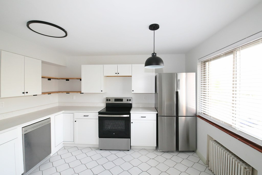 A modern kitchen with white cabinets and a black and white tiled floor.
