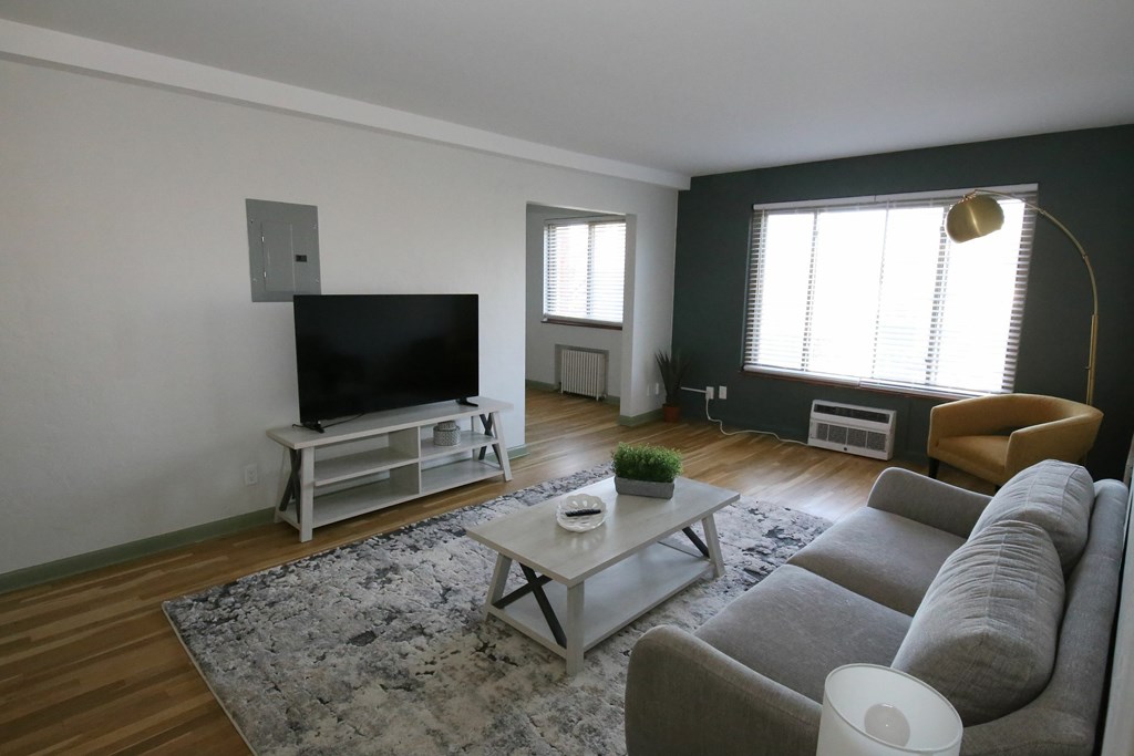 A living room with a grey couch, a white coffee table, and a flat screen TV.