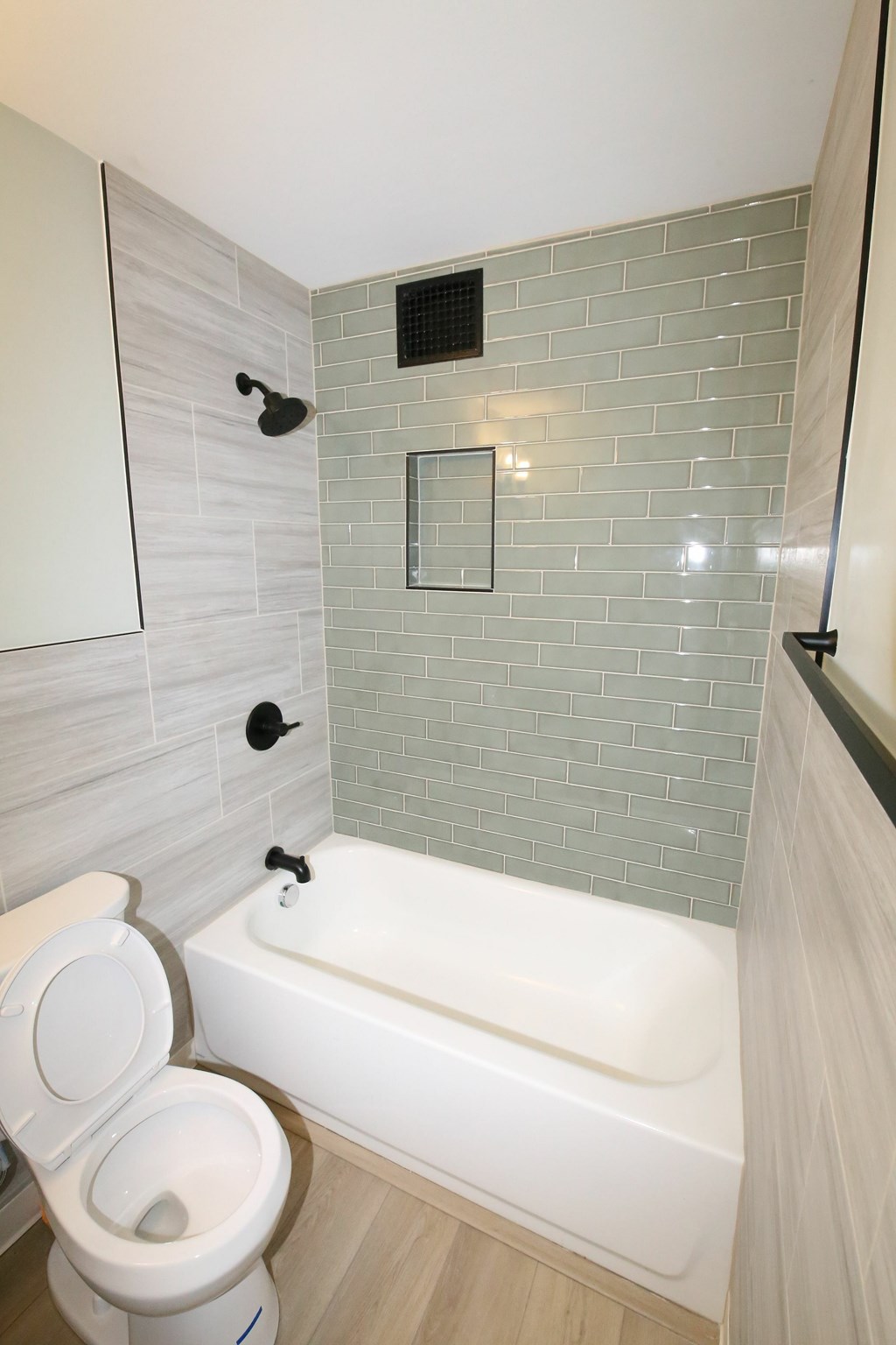 A white toilet sits next to a bathtub in a bathroom.