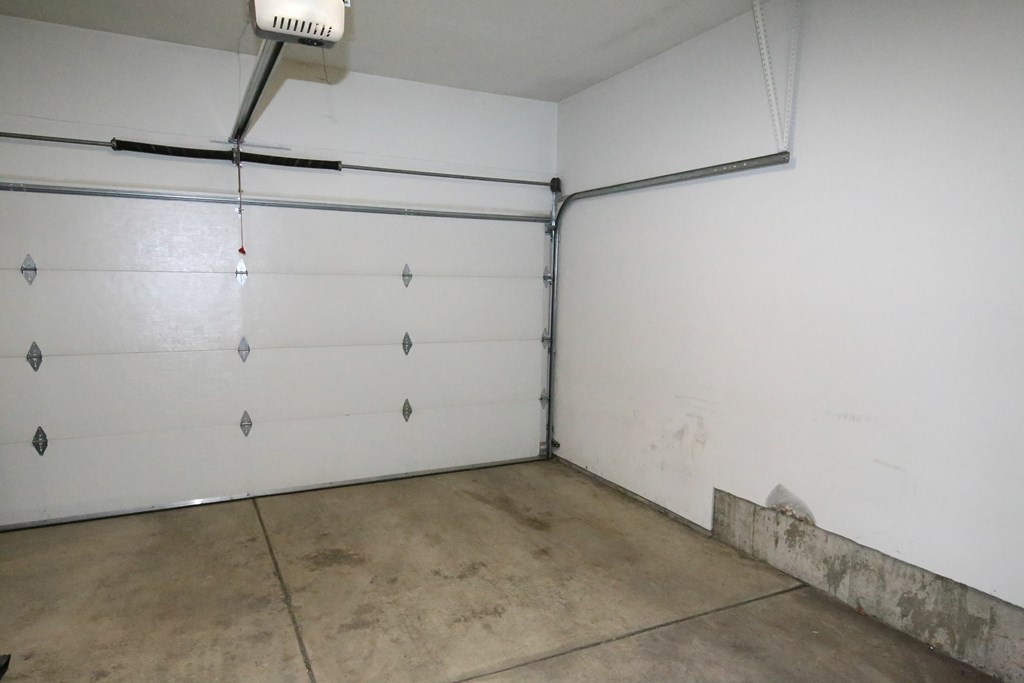 A white wall with a vent and a pipe.