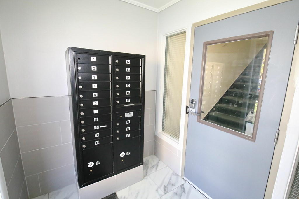 A black elevator control panel with white buttons is next to a glass door.