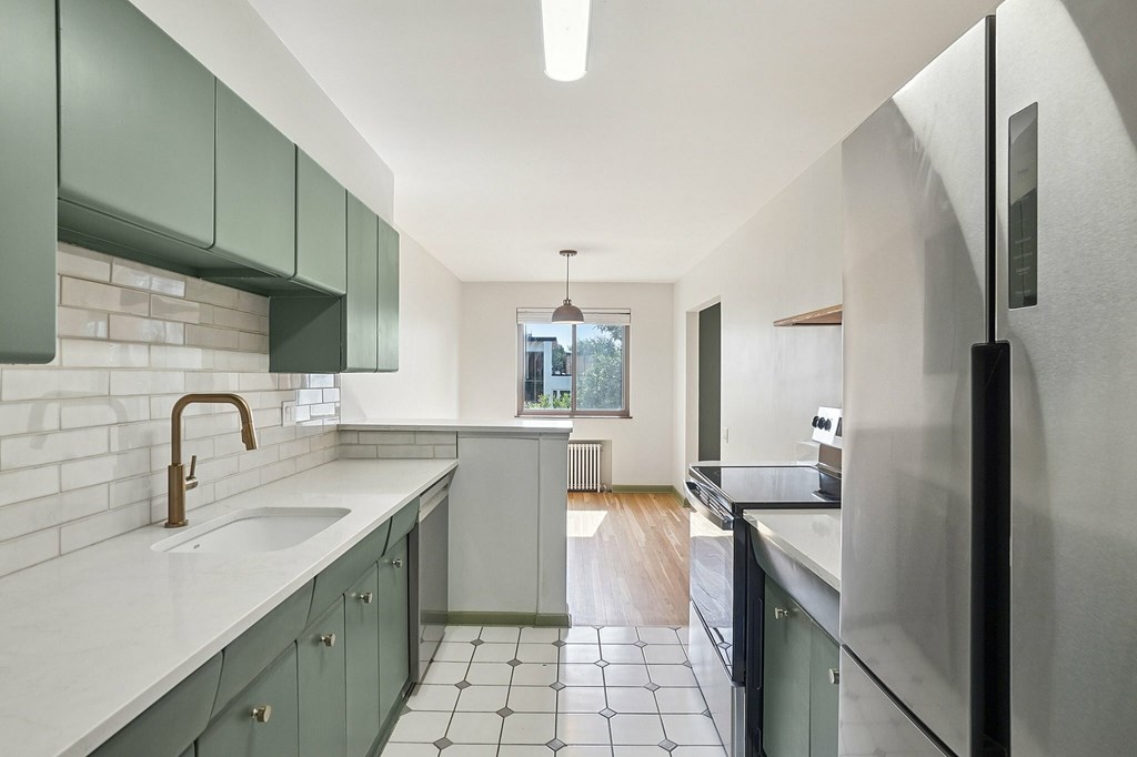 A kitchen with green cabinets and a white counter top.