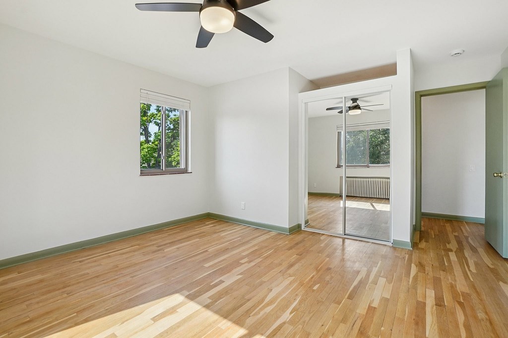 A room with a ceiling fan and wooden flooring.