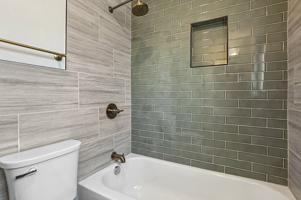 A white toilet sits next to a white bathtub in a bathroom.