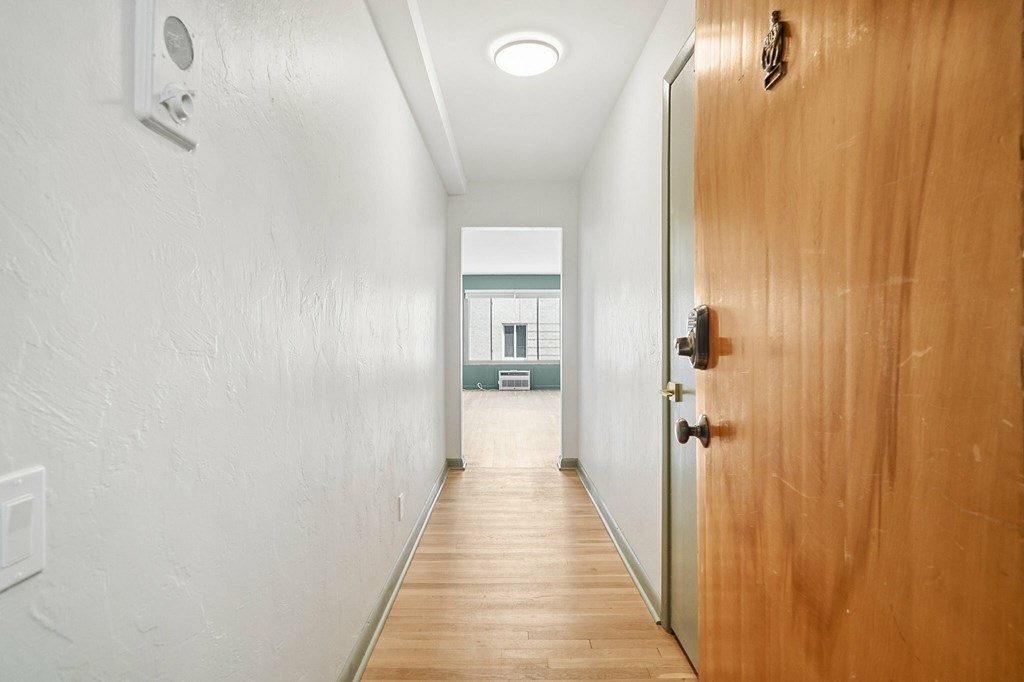 A long hallway with a wooden door on the right.