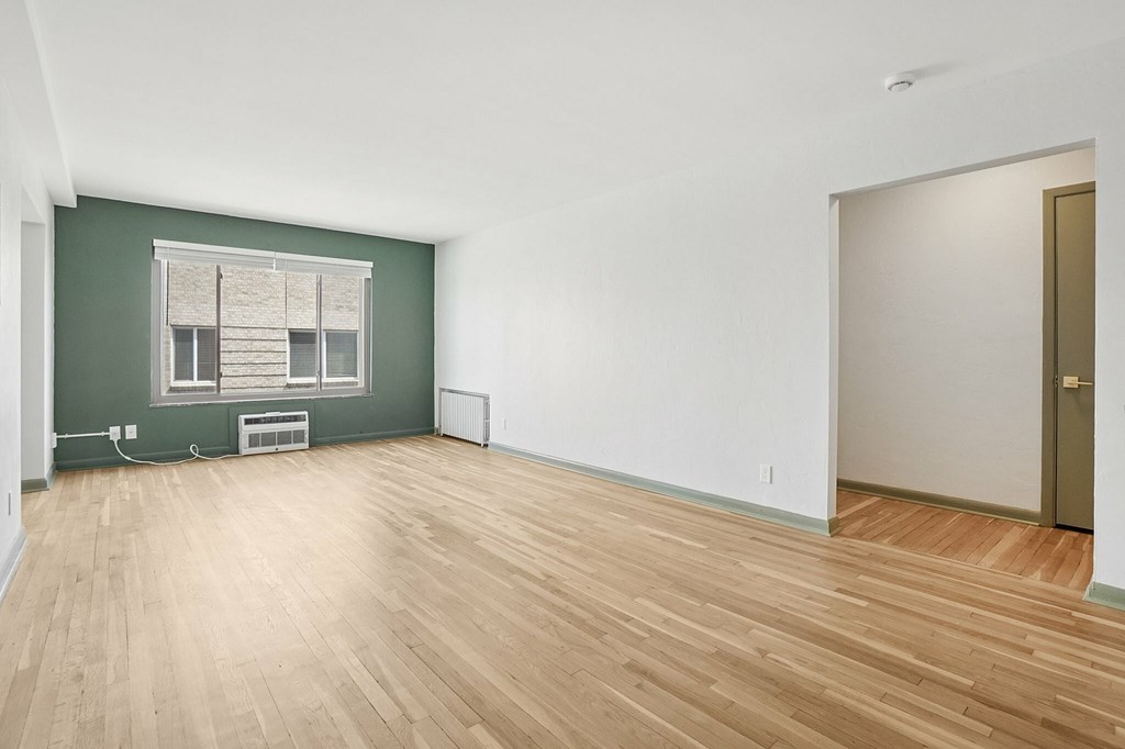 A room with wooden flooring and a window with blinds.
