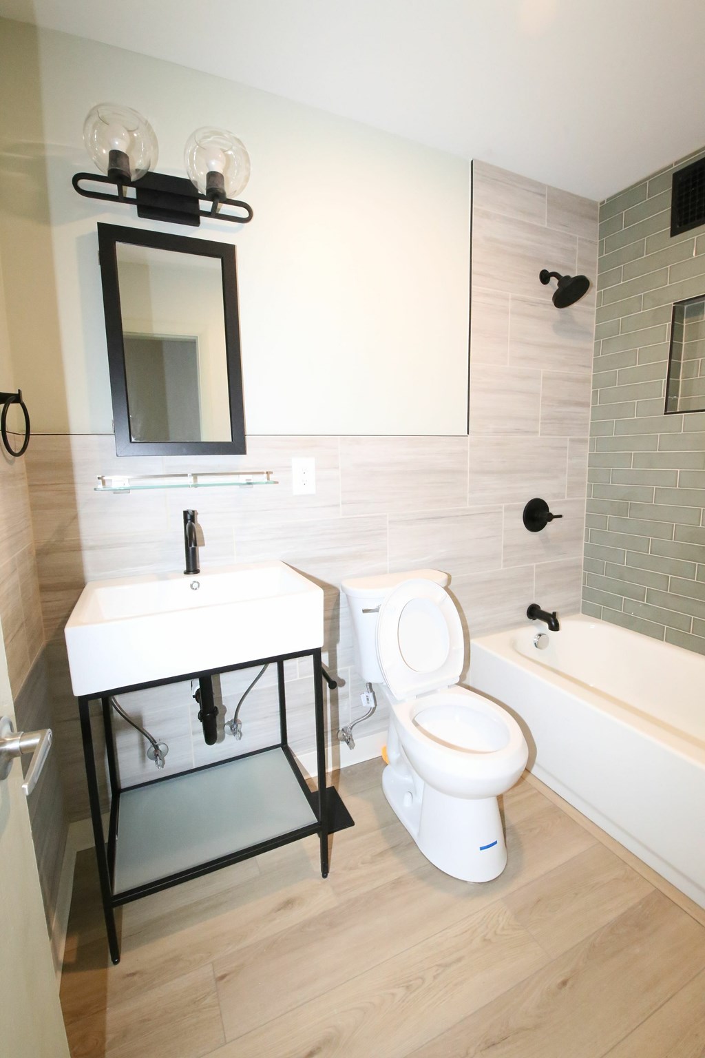 A white toilet with a black frame and a white sink with a black frame and a mirror above the sink.