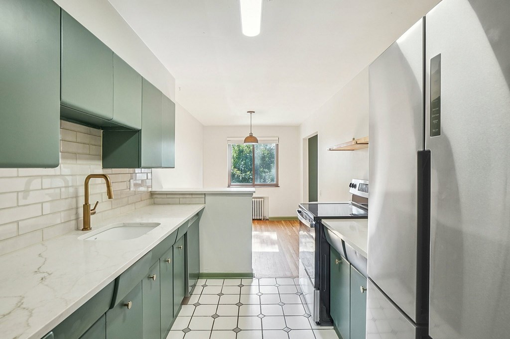 A kitchen with green cabinets and a white fridge.