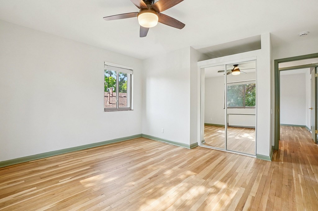 A room with a ceiling fan and wooden flooring.