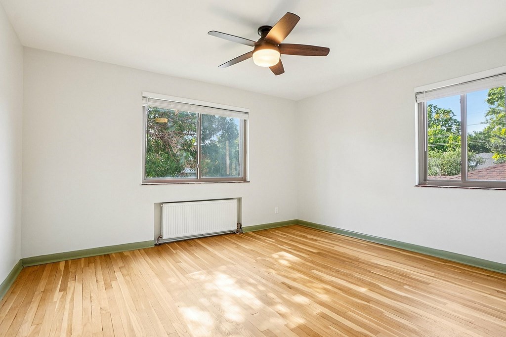 A room with a ceiling fan and two windows.