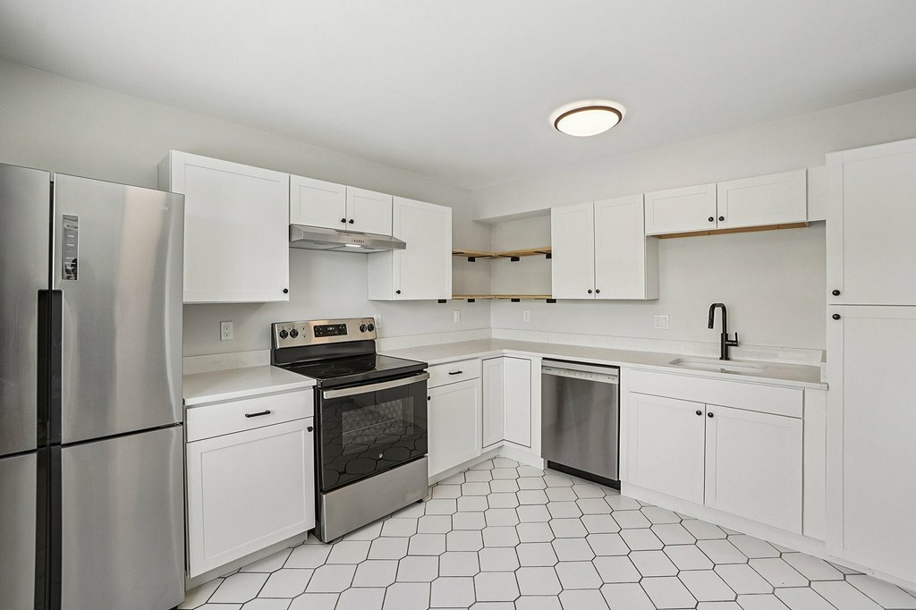 A kitchen with white cabinets and a black and white floor.