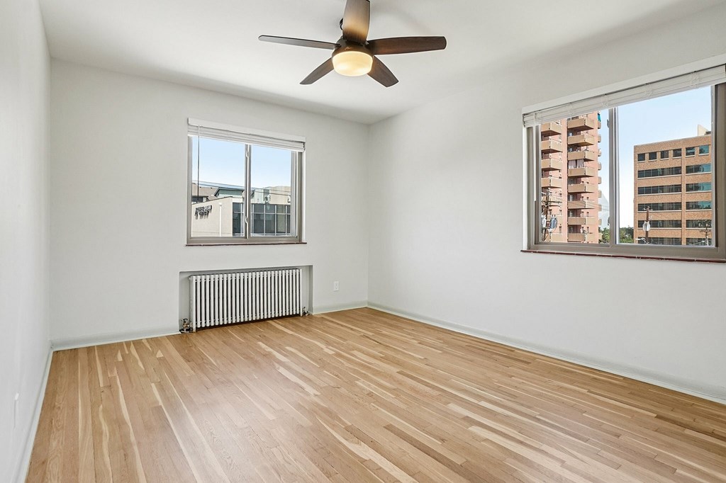 Empty room with wooden floor and ceiling fan.