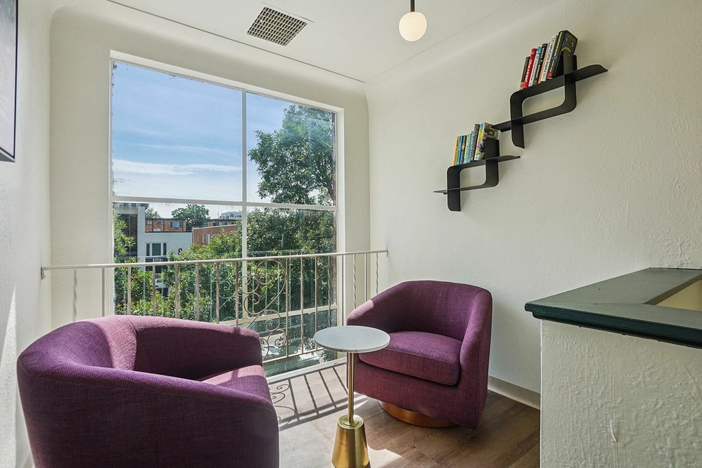 A balcony with a purple chair and a table with a lamp on it.
