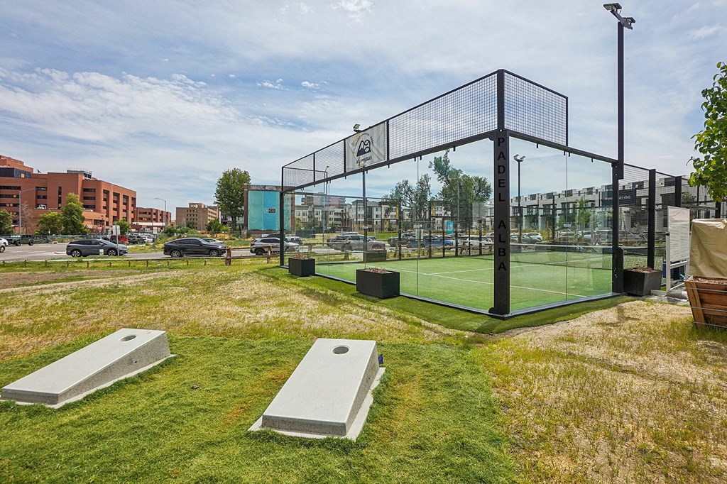 A tennis court with a black fence and two grey benches.