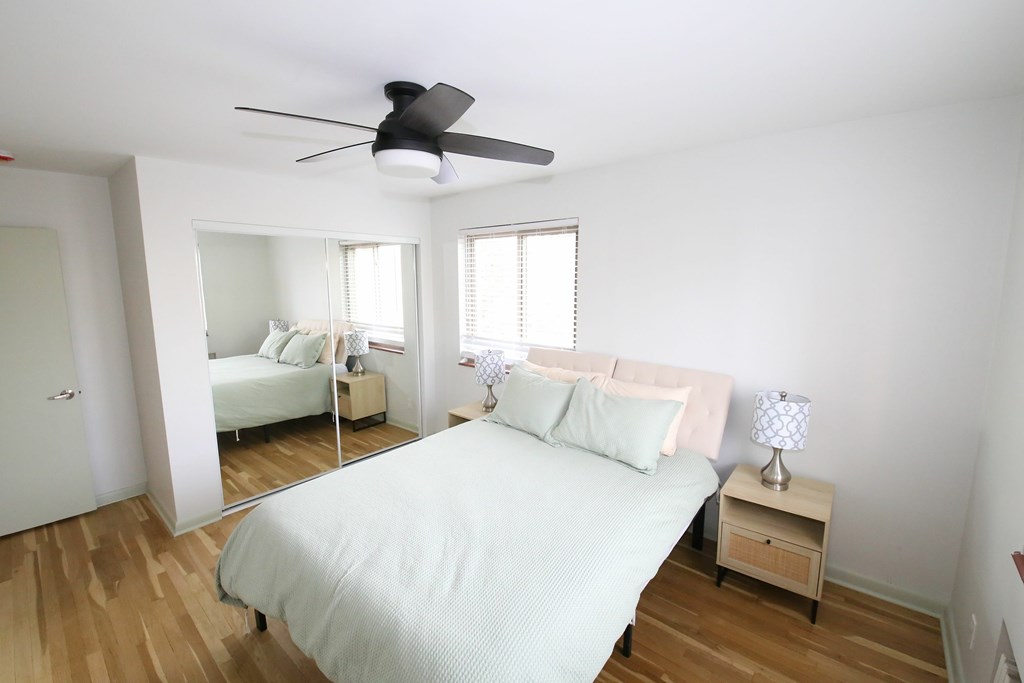 A bedroom with a bed, nightstand, and mirror.