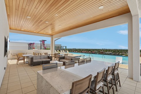 A modern outdoor dining area with a view of the pool and beach.
