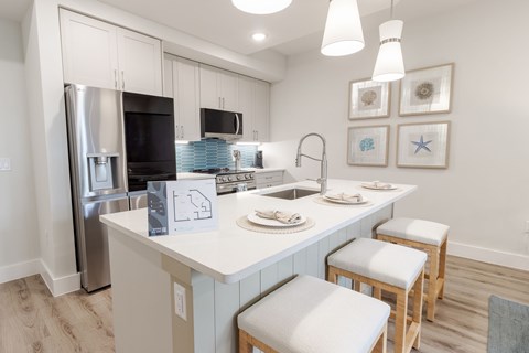 A kitchen with a white counter top and stools.