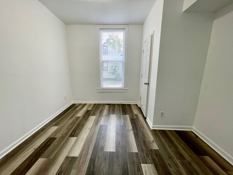 A room with a window and wooden flooring.