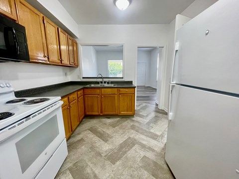 A kitchen with a white stove top oven and a white refrigerator.
