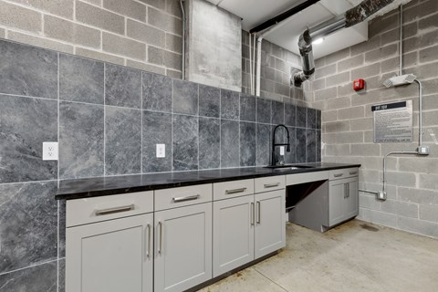 A kitchen with grey cabinets and a black countertop.